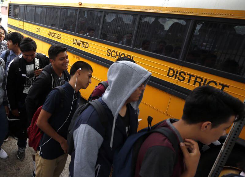 Students line up for their buses at a district stop near Jefferson High School in Los Angeles on the first day of classes in 2015. In California, 58% of Latinos attend “intensely segregated schools,” a recent report says. (Mark Boster / Los Angeles Times)